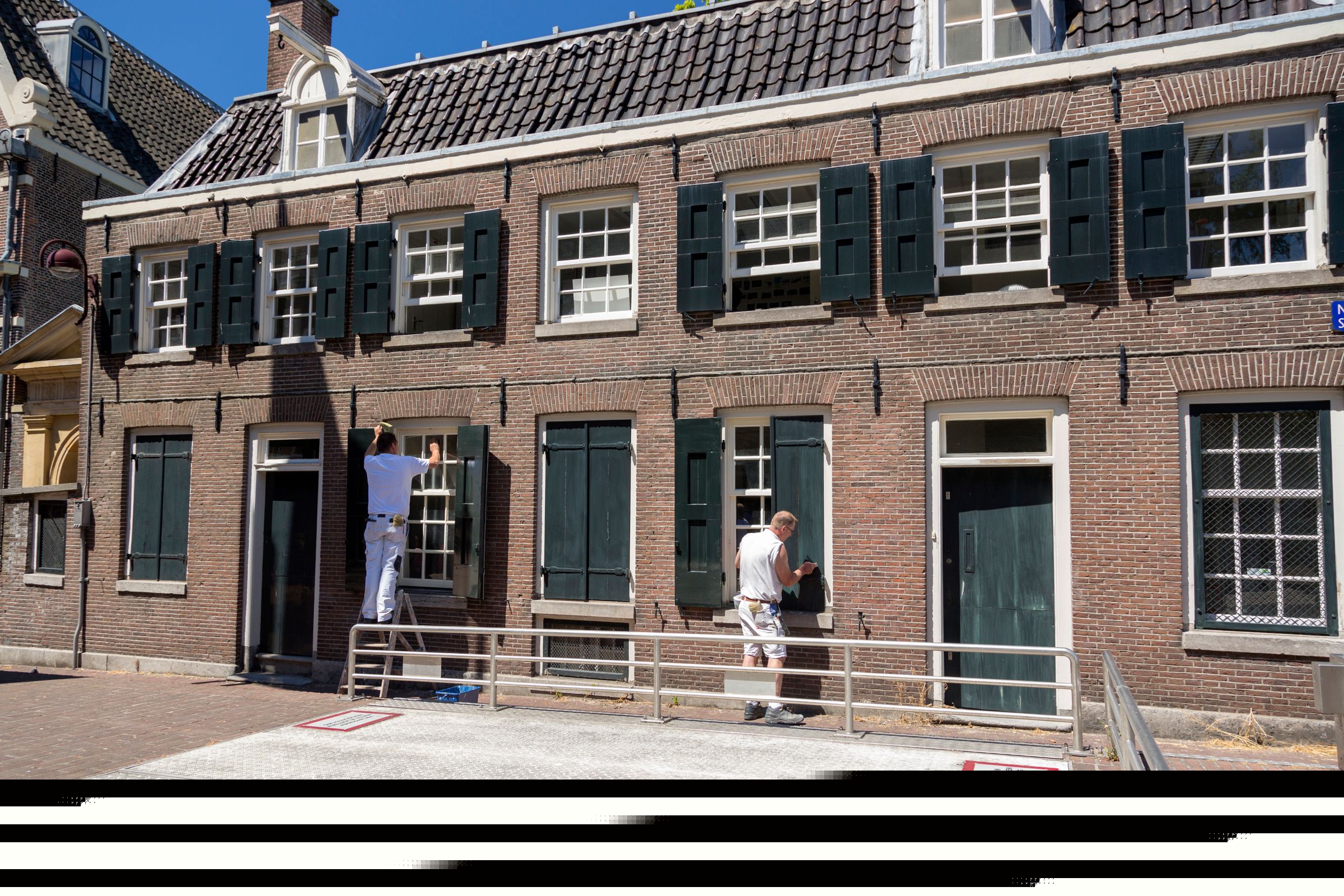 Professional painters refreshing a home's windows and shutters