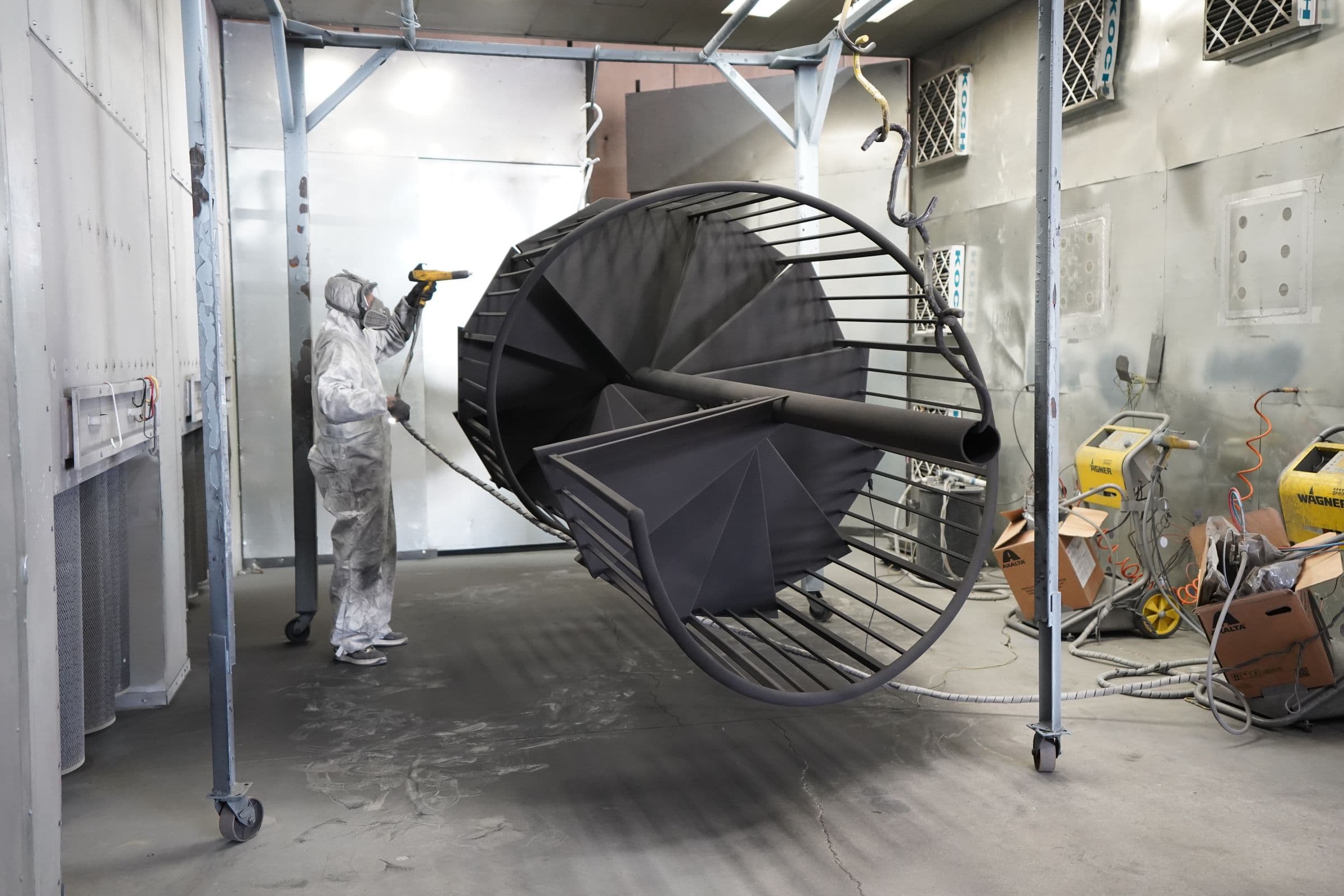 Coating specialist in protective equipment spray-painting an industrial structure