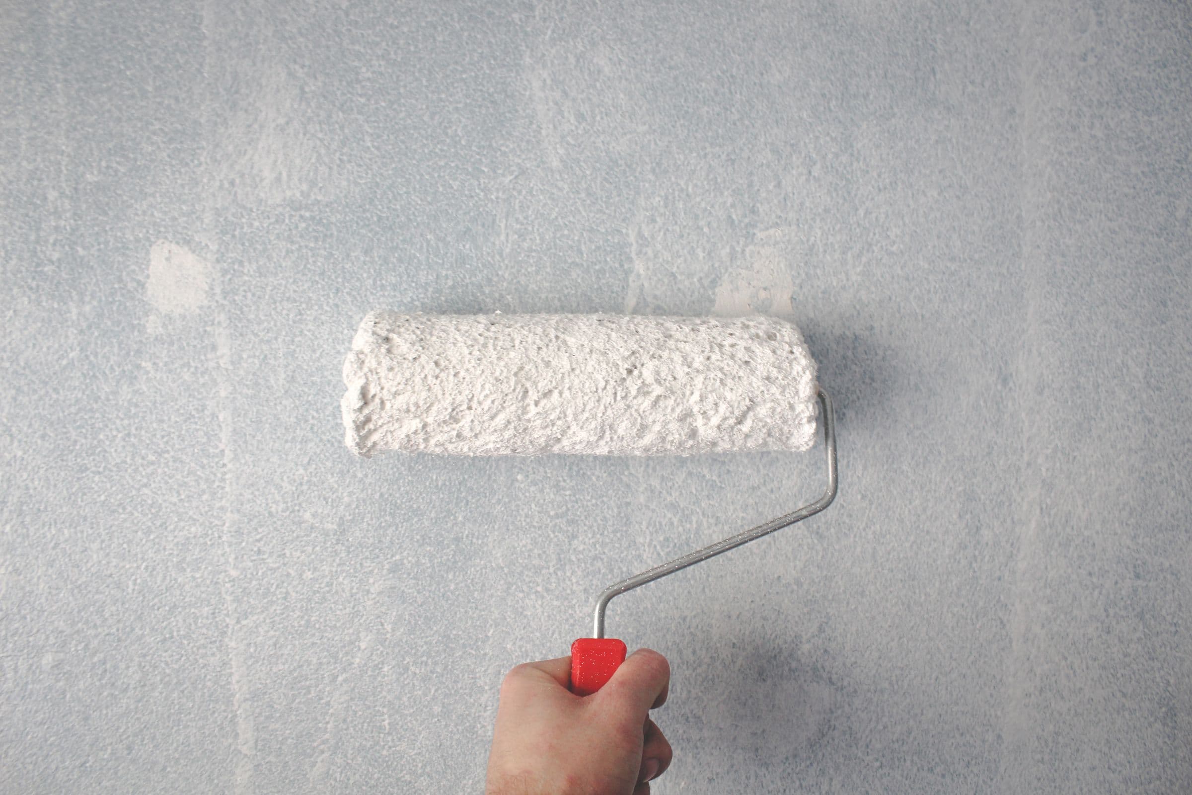 Painter applying fresh paint to an interior wall with a roller